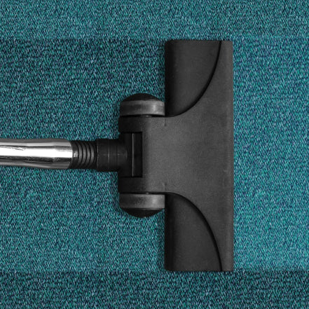 Vacuum cleaning a dirty blue carpet 