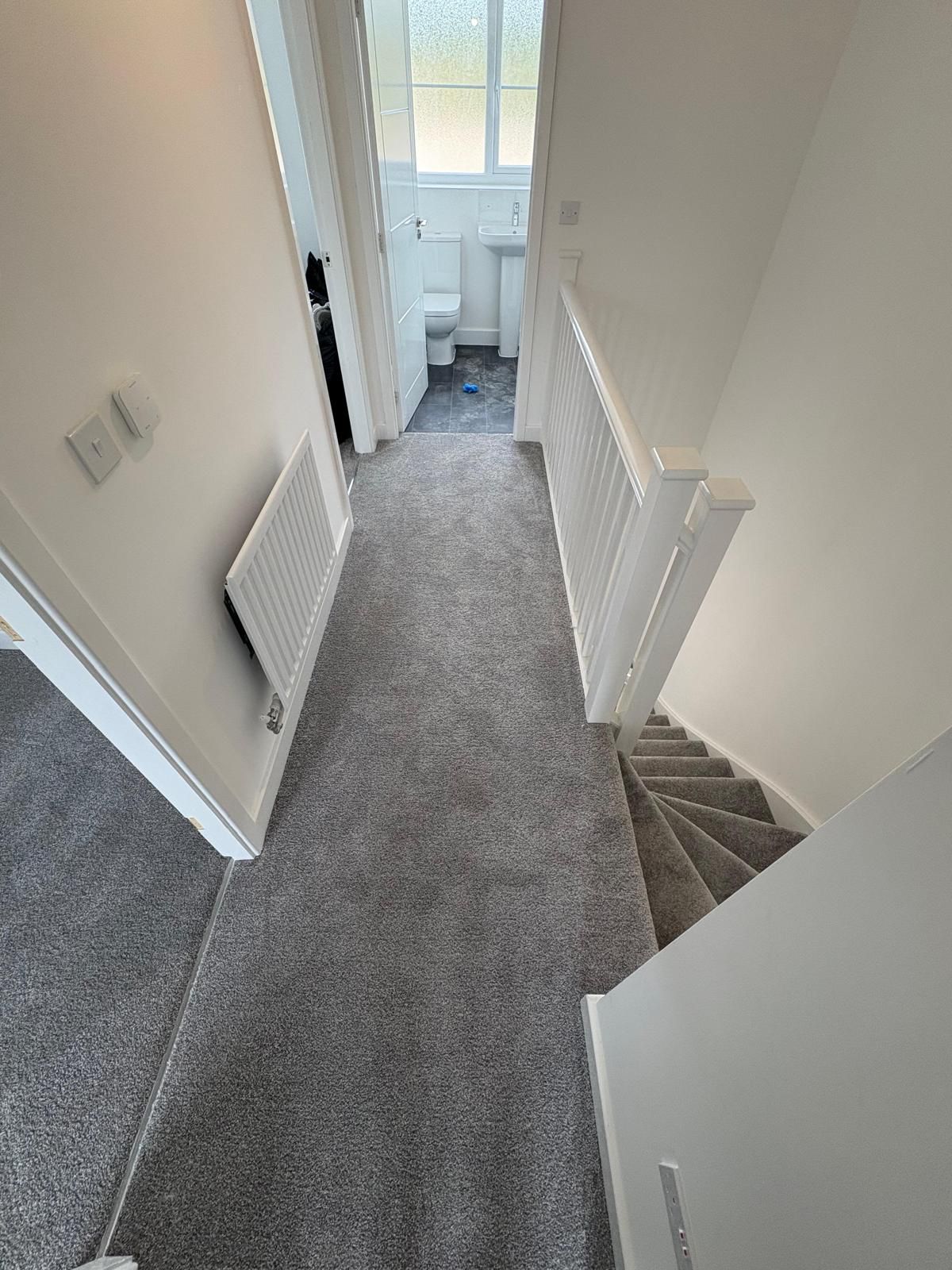 Staircase with carpeted steps and a white railing in a home interior.